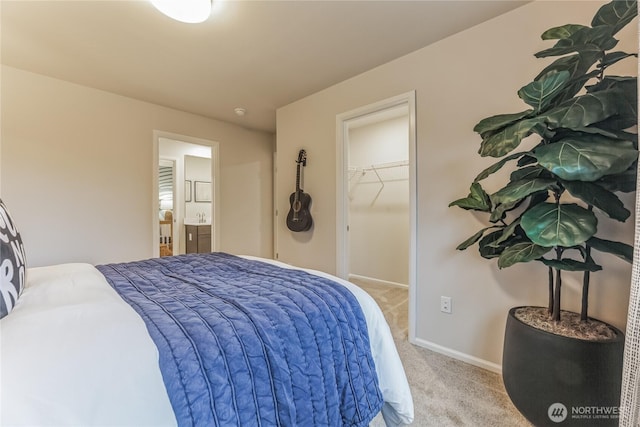 carpeted bedroom with baseboards, connected bathroom, a walk in closet, and a closet