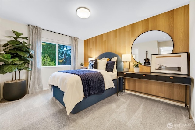 bedroom featuring baseboards, wood walls, and carpet