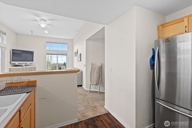 kitchen featuring freestanding refrigerator, a ceiling fan, open floor plan, dark wood-type flooring, and a sink