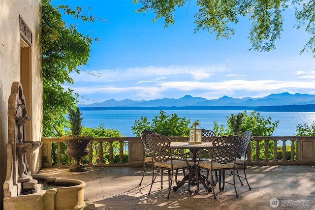view of patio with outdoor dining area and a water and mountain view
