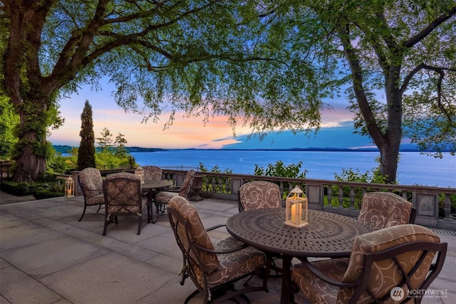 patio terrace at dusk with a water view and outdoor dining area