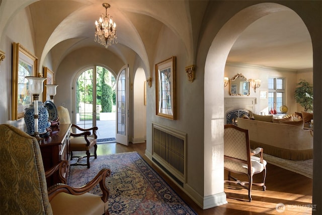 entryway featuring a notable chandelier, baseboards, wood finished floors, arched walkways, and a fireplace