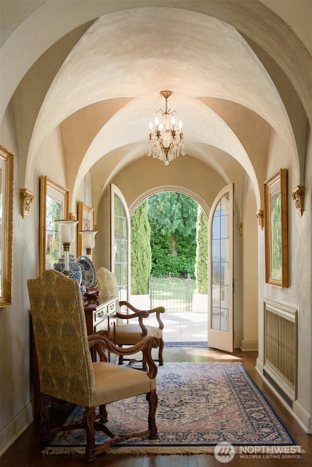 sitting room with a chandelier, arched walkways, baseboards, and wood finished floors