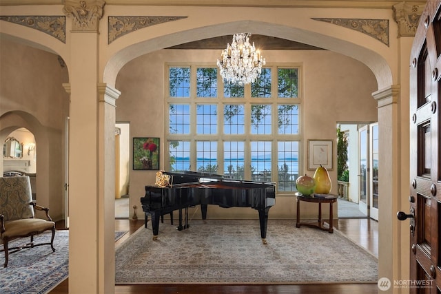 sitting room featuring a towering ceiling, arched walkways, and a notable chandelier
