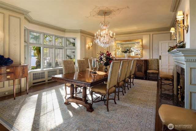 dining space with an inviting chandelier, a fireplace, ornamental molding, and radiator heating unit