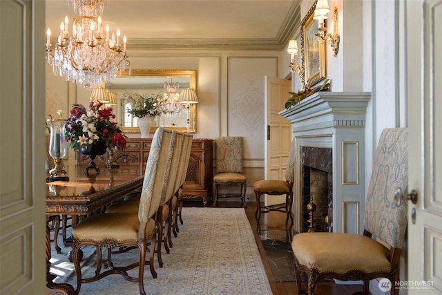 dining room with an inviting chandelier, wood finished floors, a wainscoted wall, a premium fireplace, and a decorative wall