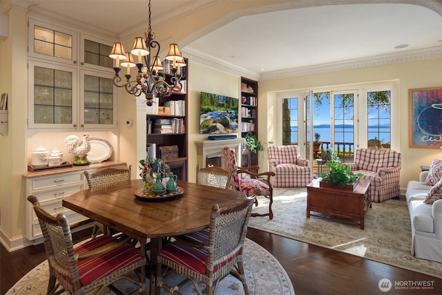 dining space featuring crown molding, a notable chandelier, dark wood-style floors, and built in features