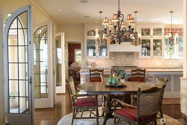 dining space featuring ornamental molding, a notable chandelier, a healthy amount of sunlight, and dark wood-type flooring