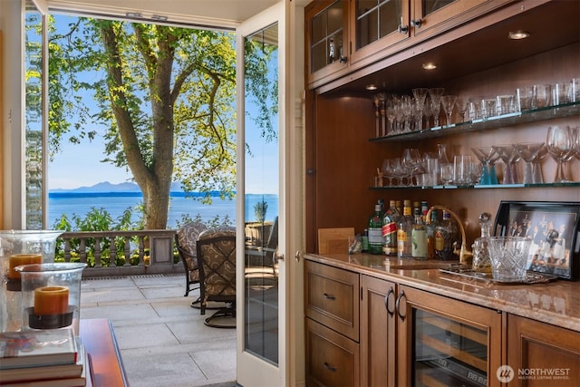 bar with a water view, a sink, a bar, and beverage cooler