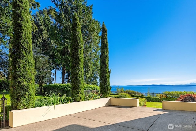 view of patio featuring a water view and fence
