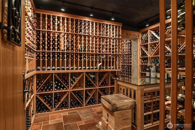 wine cellar featuring rail lighting and stone finish floor