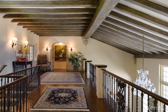 hallway with beamed ceiling, an upstairs landing, a chandelier, and wood finished floors