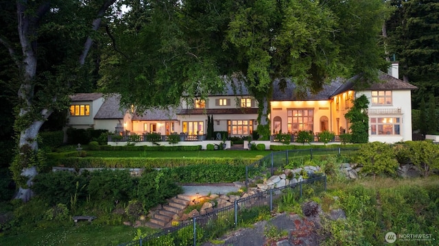 rear view of house featuring a chimney, stucco siding, and fence