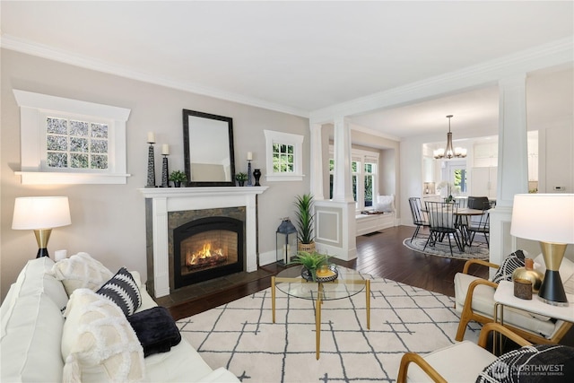 living area with ornamental molding, a lit fireplace, ornate columns, and wood finished floors