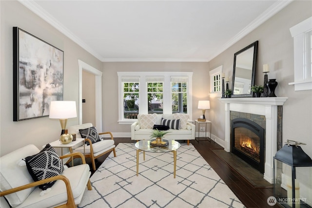 living room featuring baseboards, ornamental molding, wood finished floors, and a tiled fireplace