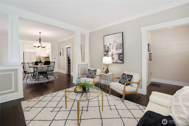 living area featuring baseboards, decorative columns, ornamental molding, and wood finished floors