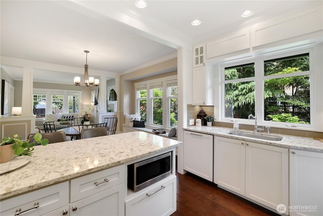kitchen with a sink, dishwasher, white cabinetry, stainless steel microwave, and ornamental molding