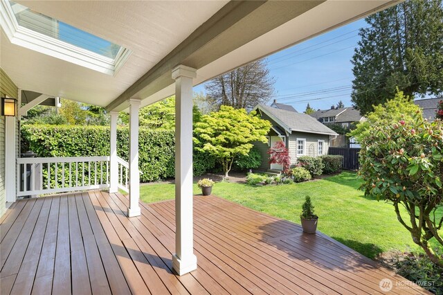 wooden terrace with a lawn, fence, and an outdoor structure