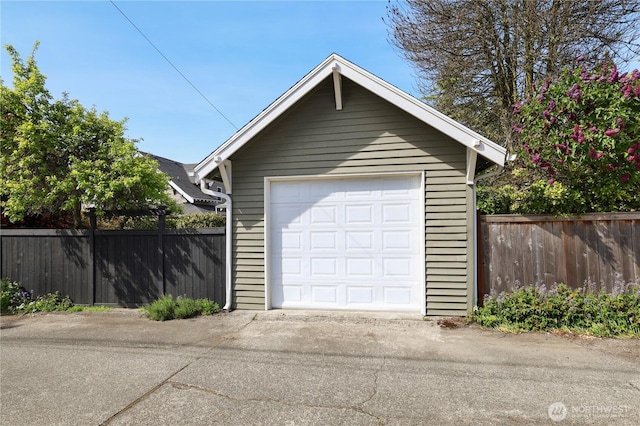 detached garage with fence and concrete driveway