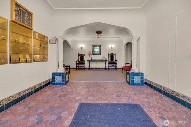 corridor featuring arched walkways, decorative columns, and stone finish flooring