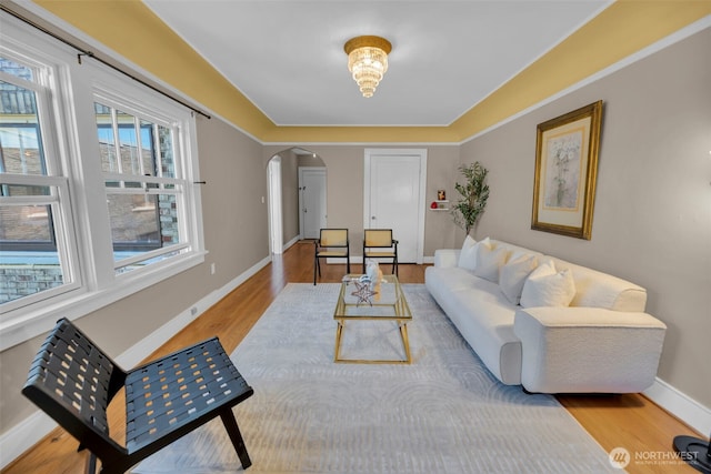 living room featuring arched walkways, wood finished floors, and baseboards