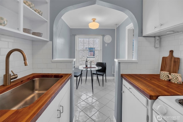 kitchen featuring wood counters, a sink, stove, tasteful backsplash, and ornamental molding