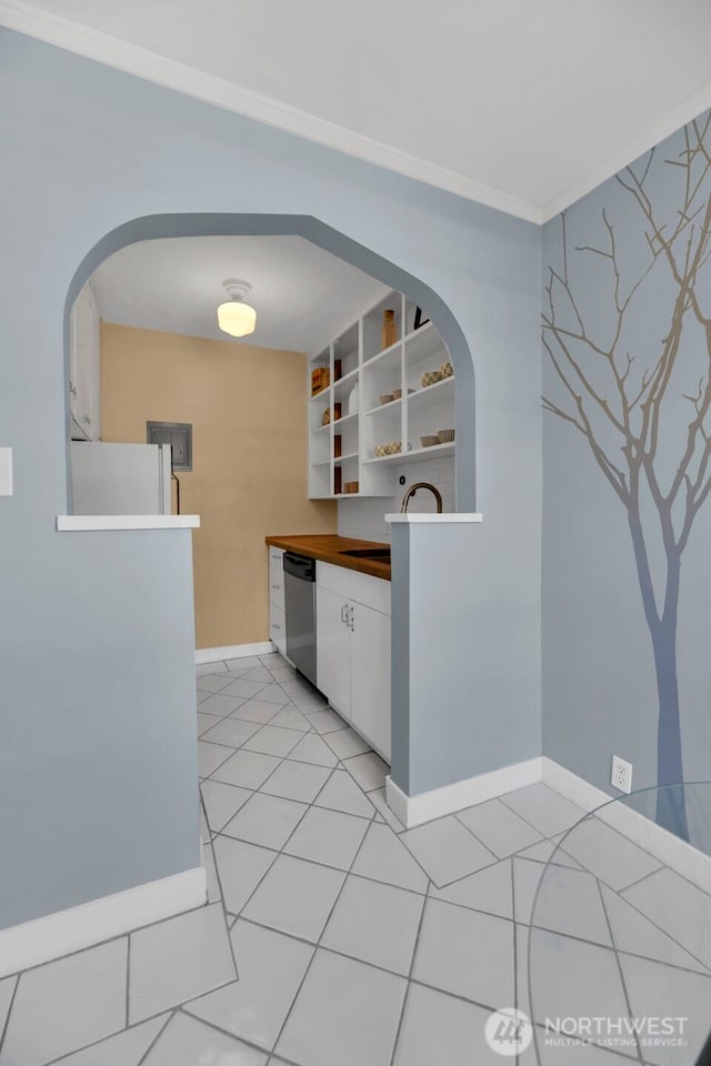 kitchen with a sink, white cabinets, baseboards, light tile patterned floors, and freestanding refrigerator