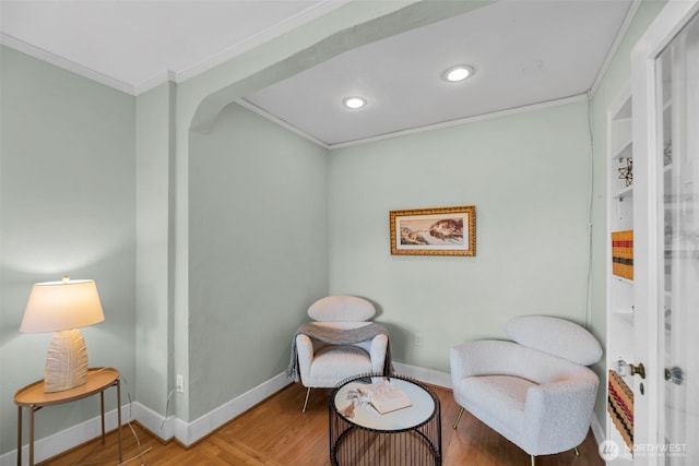 sitting room with crown molding, wood finished floors, baseboards, and recessed lighting