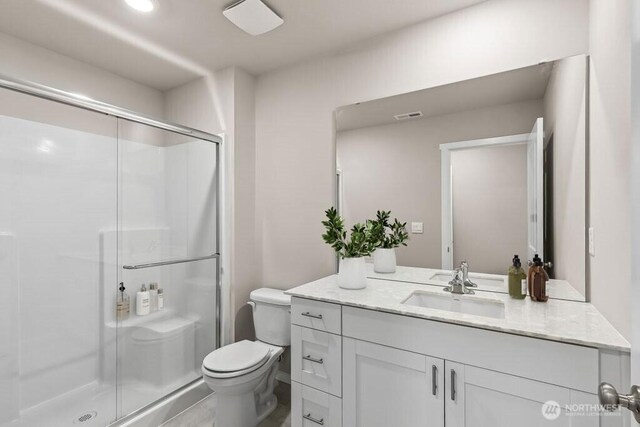 full bath featuring vanity, a shower stall, toilet, and visible vents