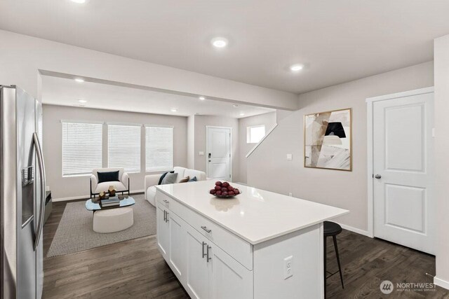 kitchen featuring stainless steel fridge with ice dispenser, a breakfast bar area, recessed lighting, white cabinetry, and dark wood-style floors