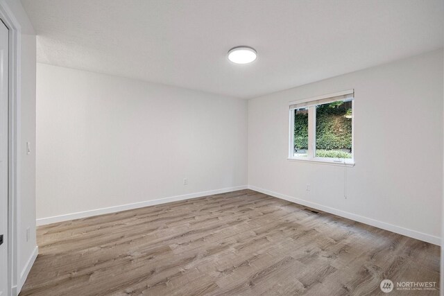 empty room featuring baseboards, visible vents, and wood finished floors