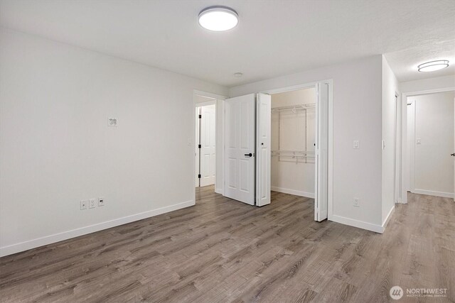 unfurnished bedroom with light wood-style floors, baseboards, and a closet
