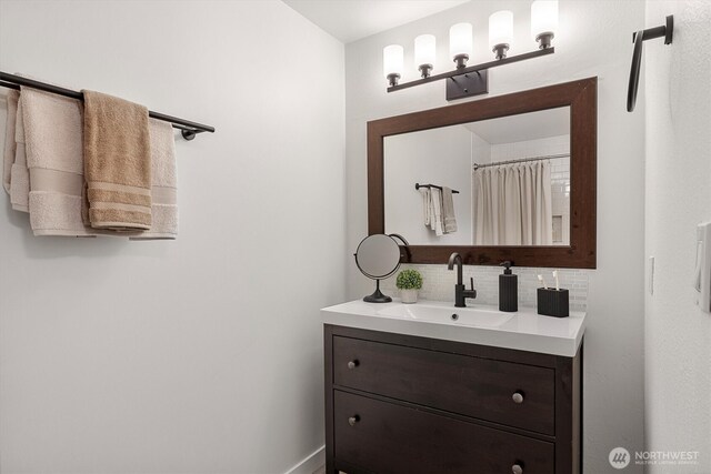 full bath with vanity, baseboards, and backsplash