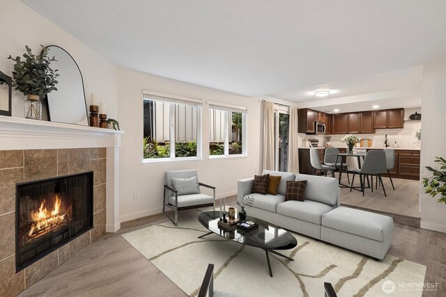 living area featuring recessed lighting, light wood-style floors, baseboards, and a fireplace