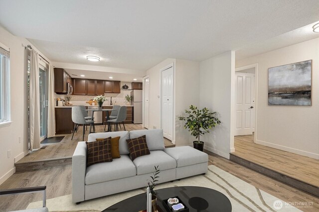 living room featuring recessed lighting, baseboards, and light wood-style flooring