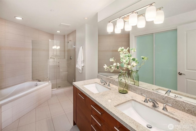 bathroom with tile patterned floors, tiled tub, a sink, and a stall shower
