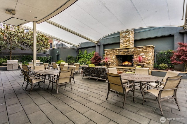 view of patio with area for grilling, an outdoor stone fireplace, and outdoor dining space