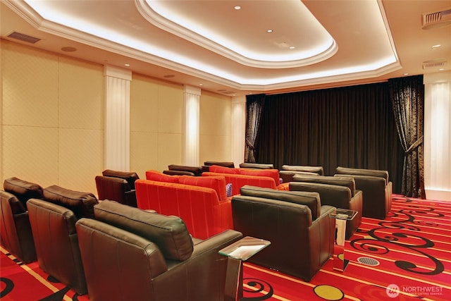 cinema room featuring a tray ceiling, visible vents, and ornamental molding