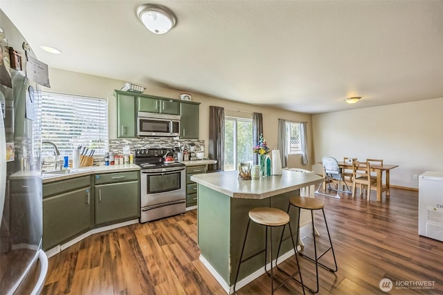 201 3rd St NE, Yelm, WA 98597 - kitchen featuring a sink, stainless steel appliances, green cabinetry, dark wood finished floors, and light countertops