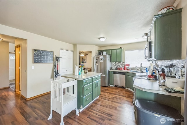 201 3rd St NE, Yelm, WA 98597 - kitchen with stainless steel appliances, dark wood finished floors, a sink, green cabinetry, and light countertops