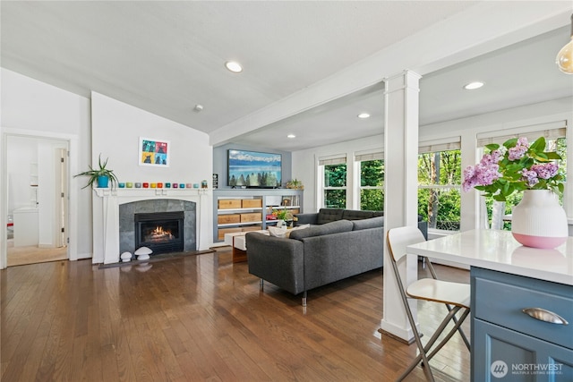 living area featuring a fireplace, dark wood finished floors, recessed lighting, ornate columns, and vaulted ceiling