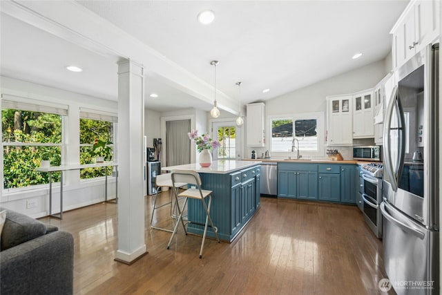 kitchen featuring stainless steel appliances, white cabinetry, a sink, and blue cabinets