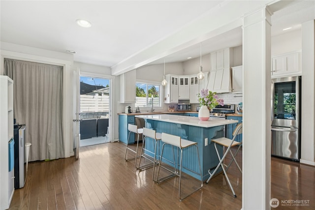 kitchen with a kitchen island, a breakfast bar, smart refrigerator, white cabinets, and backsplash