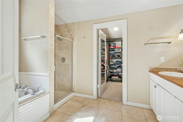 bathroom with a walk in closet, a garden tub, a stall shower, vanity, and tile patterned floors