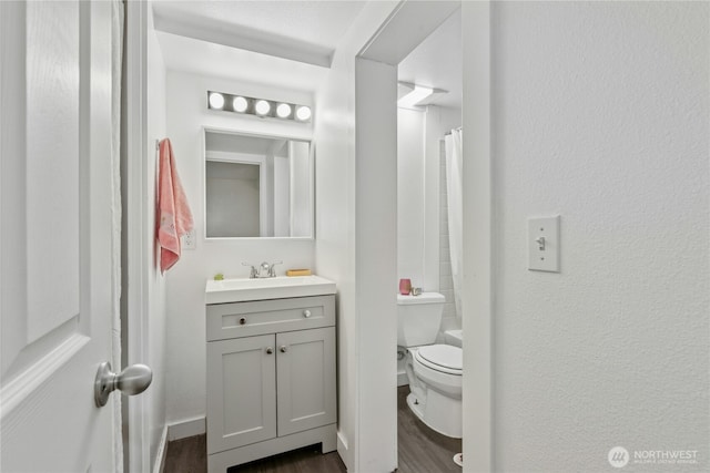 full bath with vanity, a textured wall, wood finished floors, and toilet