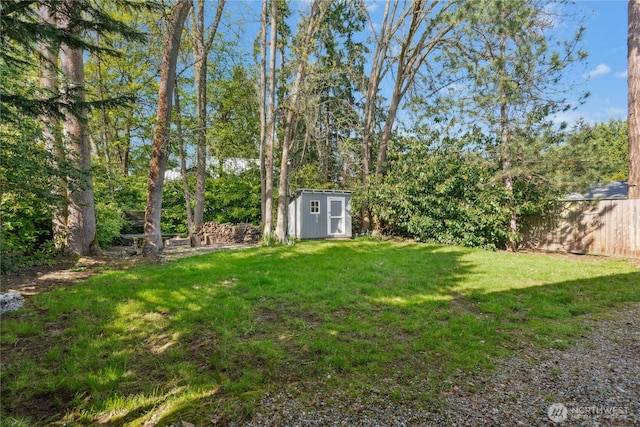 view of yard featuring a storage unit, fence, and an outbuilding
