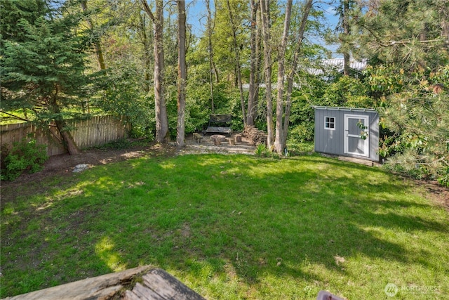 view of yard featuring fence, a storage unit, and an outbuilding