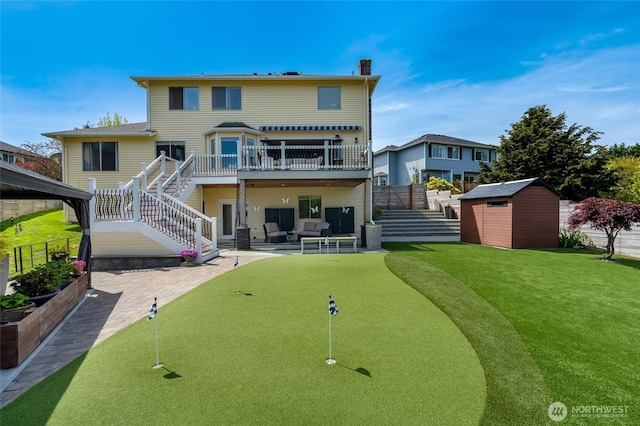 rear view of property featuring stairs, a storage shed, a deck, a putting green, and an outbuilding