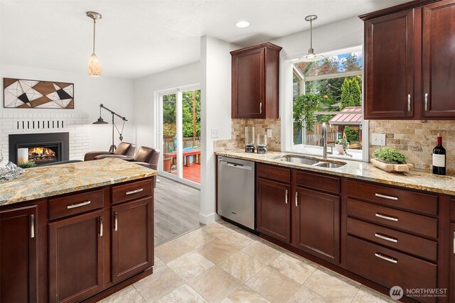 kitchen with pendant lighting, tasteful backsplash, a fireplace, stainless steel dishwasher, and a sink