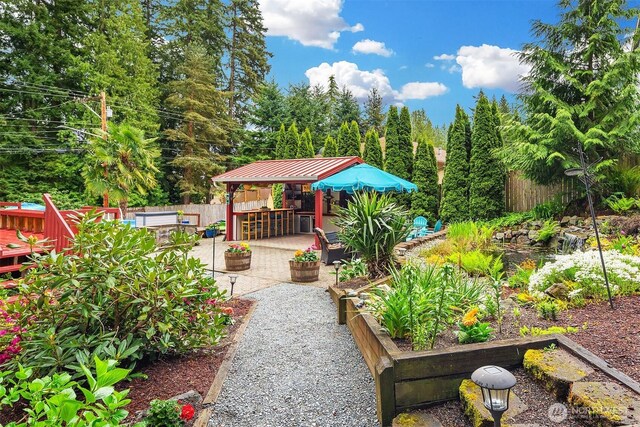 view of home's community featuring fence, a vegetable garden, outdoor dry bar, a patio area, and a hot tub
